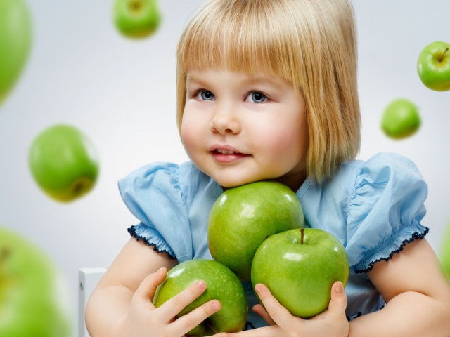 Маленькая девочка блондинка с зелеными яблоками