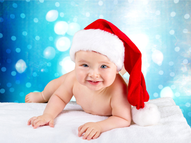 Маленький голубоглазый ребенок в красном новогоднем колпаке