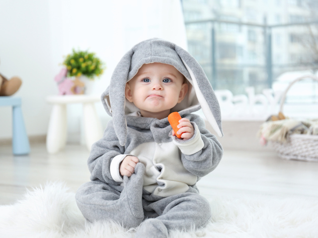 Маленький мальчик в костюме зайчика с морковкой в руке