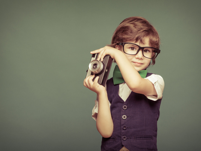 Маленький мальчик в очках с фотоаппаратом