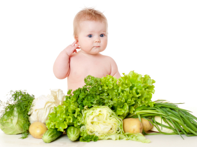 Маленький ребенок с овощами и зеленью на белом фоне