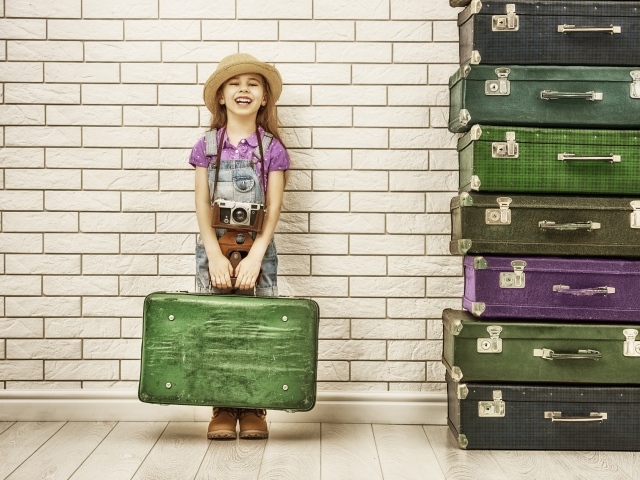 Маленькая девочка у стены с большими чемоданами