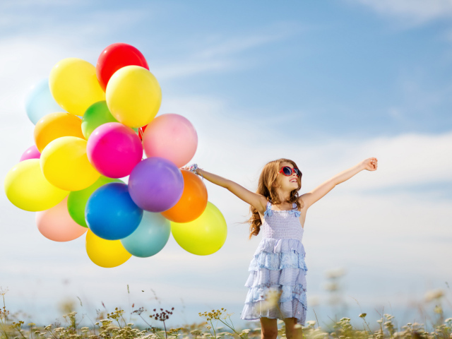 Маленькая девочка держит в руке много воздушных шаров