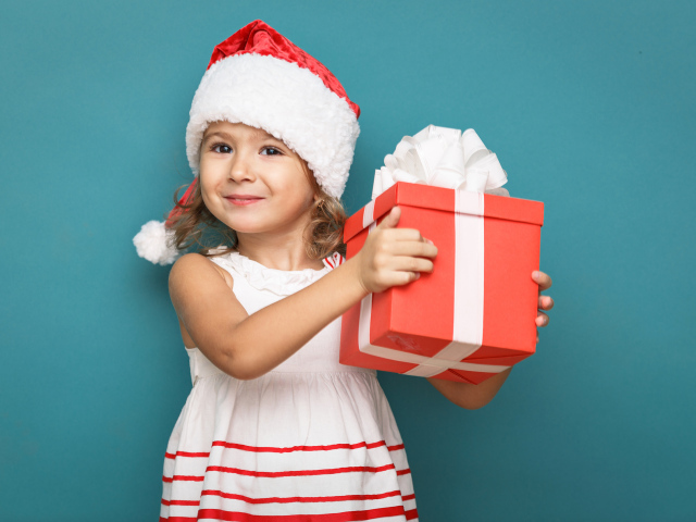 Маленькая девочка в новогоднем костюме с подарком на голубом фоне