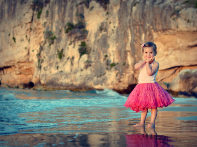 Маленькая девочка в красивой розовой юбке на пляже
