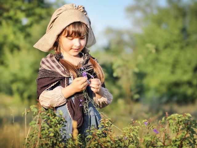 Маленькая девочка в костюме собирает травы