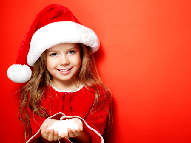 Маленькая девочка в новогодней шапке на красном фоне