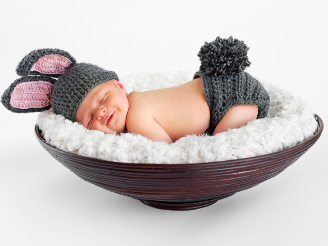 Маленький спящий грудной ребенок в вязаном костюме зайчика