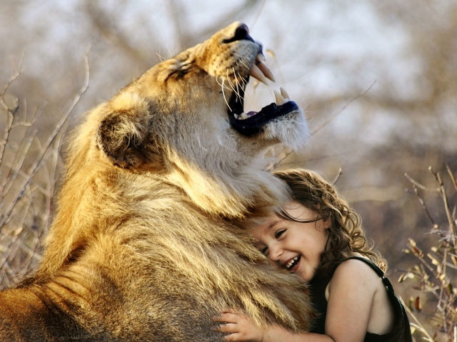Маленькая улыбающаяся девочка обнимает льва