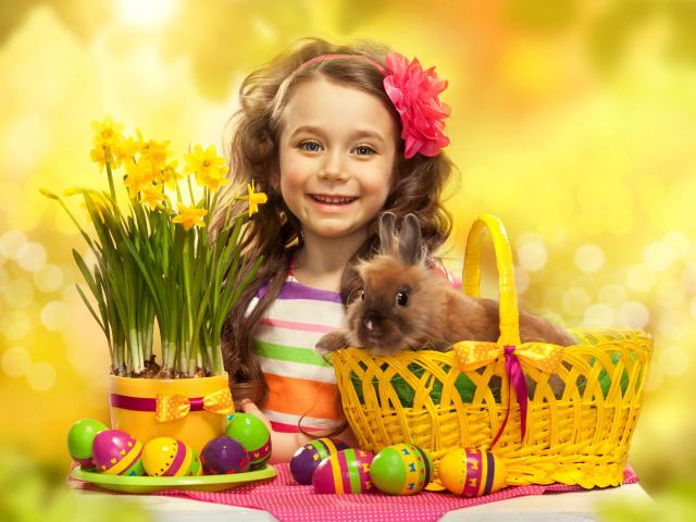 Маленькая улыбающаяся девочка с кроликом и крашеными яйцами