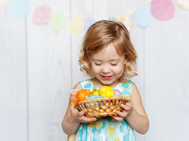 Маленькая улыбающаяся девочка с пасхальными яйцами в руках