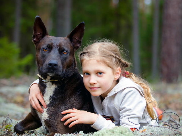 Милая голубоглазая девочка с большой черной собакой