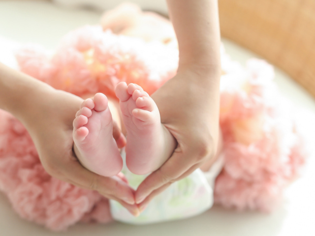 Маленькие ножки новорожденного в ладонях у мамы 