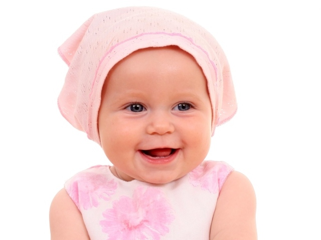 Улыбающийся грудной ребенок в розовой шапке на белом фоне
