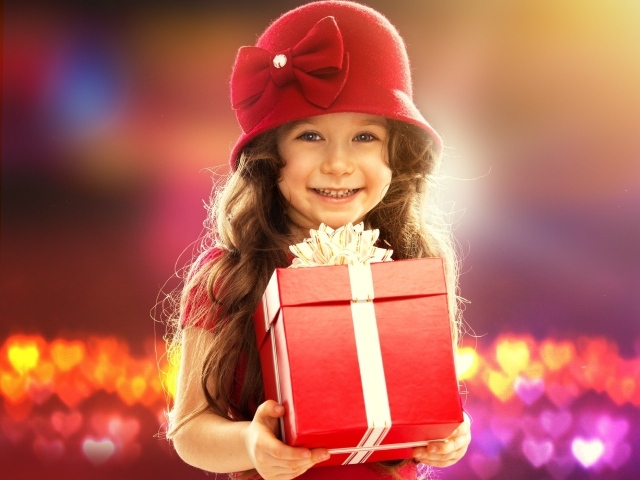 Улыбающаяся голубоглазая девочка с большим подарком в руках
