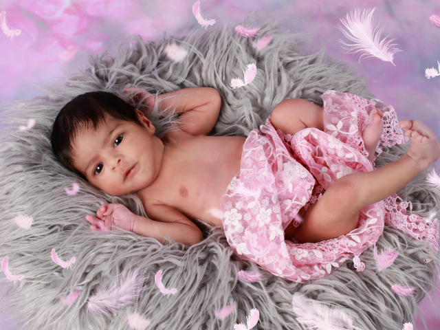 Младенец лежит на сером меховом покрывале 