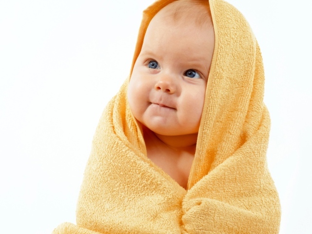 Грудной ребенок в желтом полотенце на белом фоне
