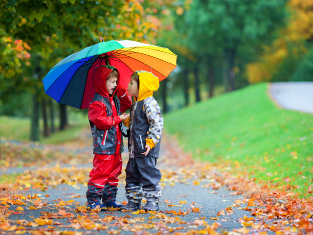 Два мальчика под разноцветным зонтом осенью