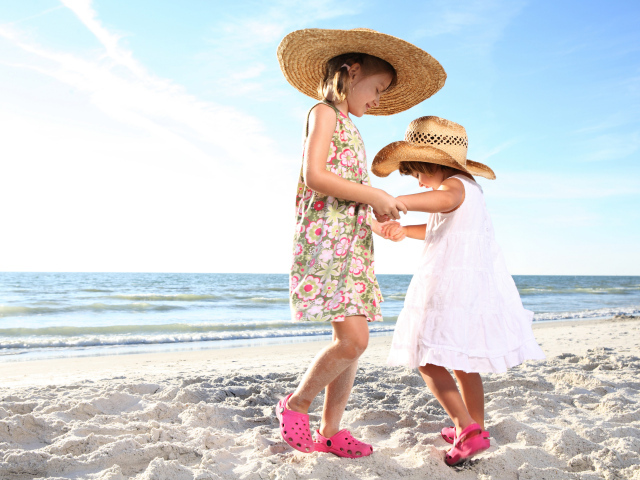 Две маленькие девочки танцуют на песке на пляже