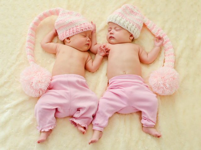 Два спящих грудных ребенка в розовых костюмах