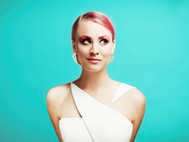 Актриса Кейли Куоко с ярким макияжем на голубом фоне