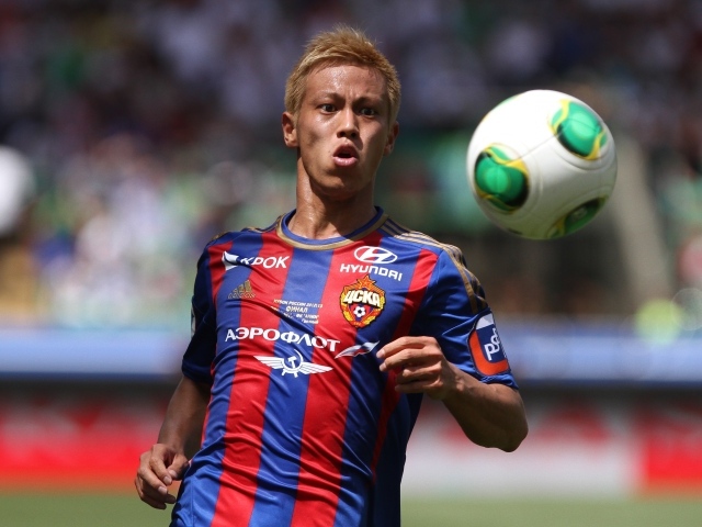 Японский футболист Кэйсукэ Хонда отбивает мяч на поле