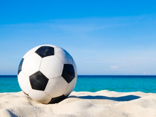 Футбольный мяч на белом песке на фоне голубого неба