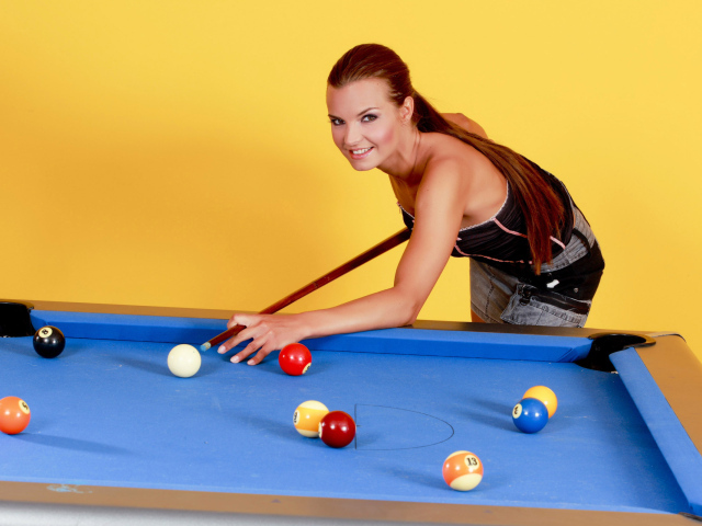Молодая девушка играет в бильярд