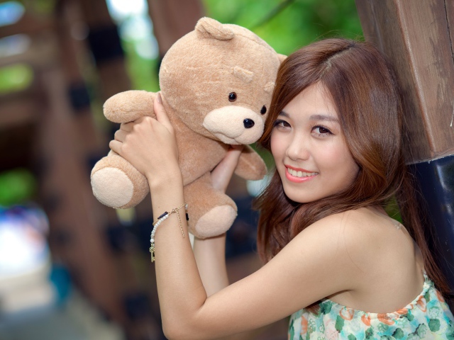 Красивая азиатка с плюшевым медведем в руках