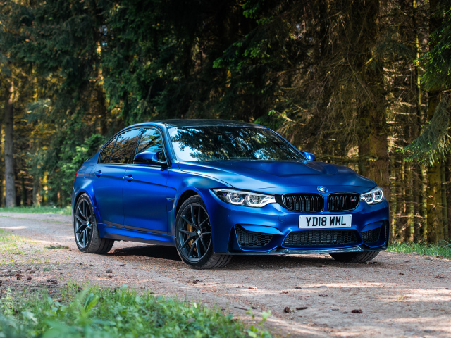 Синий автомобиль BMW M3 на фоне деревьев