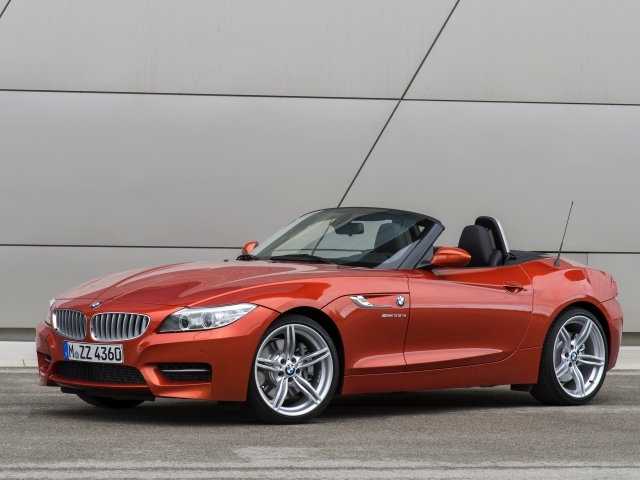 Оранжевый автомобиль кабриолет BMW Z4 на фоне стены