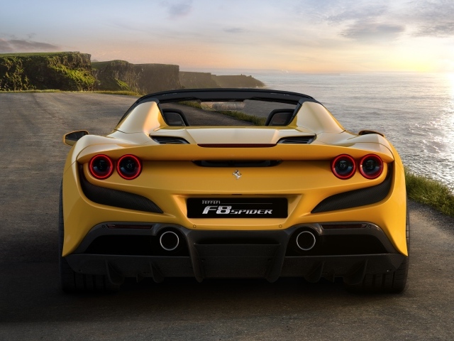 Желтый спортивный автомобиль Ferrari F8 Spider 2019 года на дороге у моря
