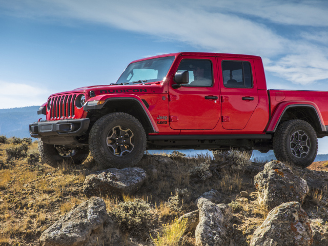 Красный пикап Jeep Gladiator Rubicon на холме с камнями