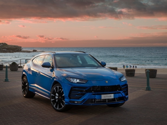 Синий автомобиль Lamborghini Urus под пасмурным небом на берегу  океана
