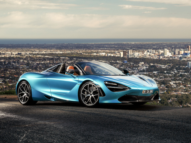 Голубой спортивный автомобиль McLaren 720S Spider 2019 года на фоне города