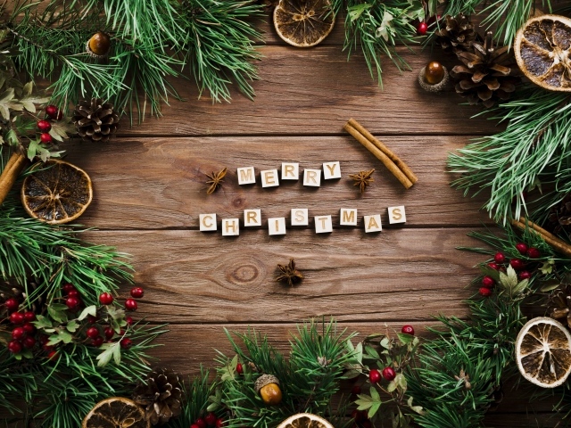 Надпись Merry Christmas на деревянном столе с еловыми ветками 
