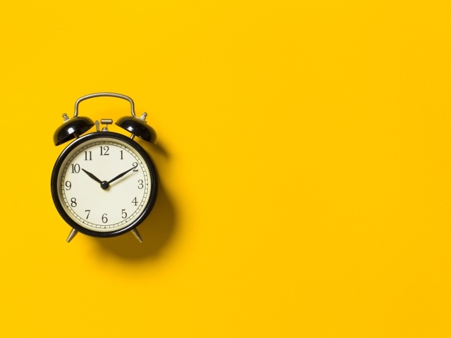 Черный будильник на желтом фоне