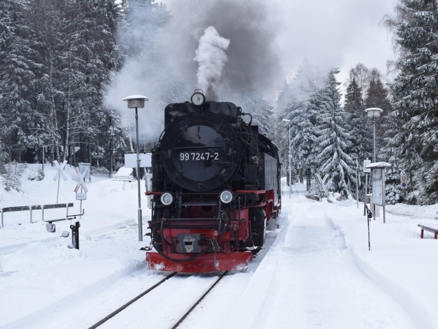 Старый локомотив на заснеженной станции у леса зимой