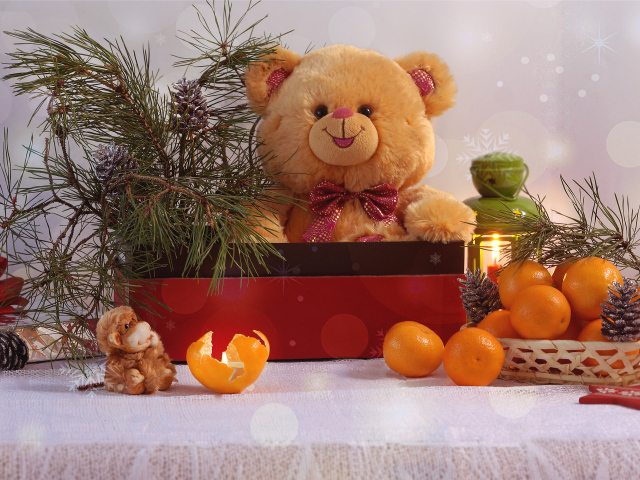 Медвежонок Тедди в коробке с еловой веткой на столе с мандаринами 
