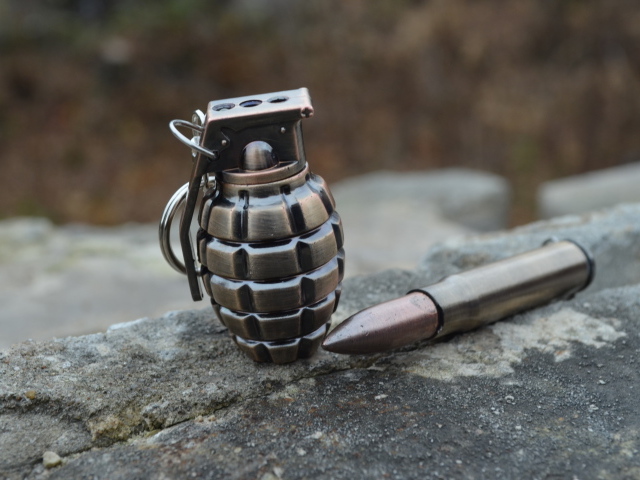 Боевая граната с патроном лежат на камне 