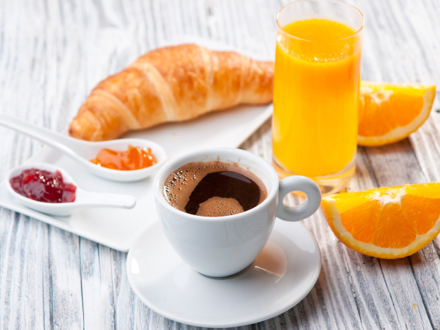 Чашка кофе на столе с соком и круассаном