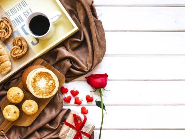 Выпечка на столе с кофе, подарком и красной розой