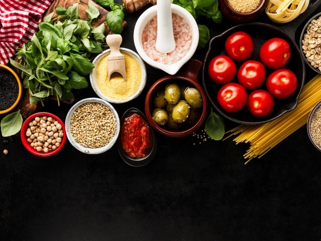 Крупы на столе с зеленью, помидорами, оливками и спагетти