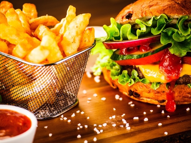 Аппетитный сочный гамбургер на доске с картошкой фри и соусом