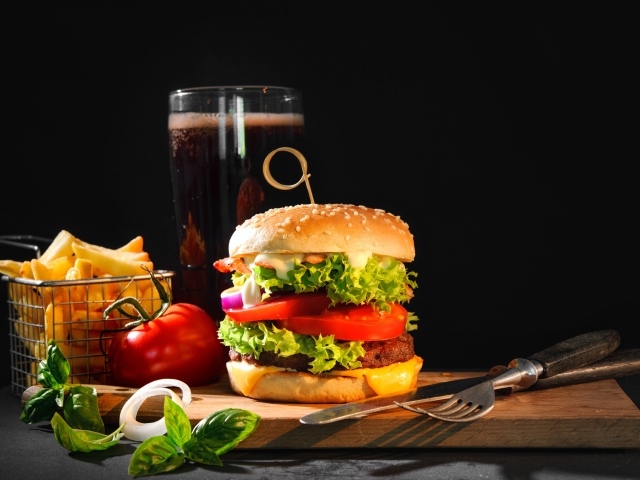 Вкусный аппетитный гамбургер на столе с пивом и картофелем фри
