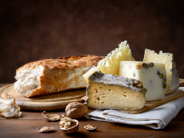 Разные виды сыра на столе батоном и грецкими орехами