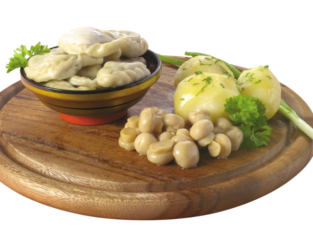 Вареники с грибами и вареной картошкой на деревянной доске на белом фоне