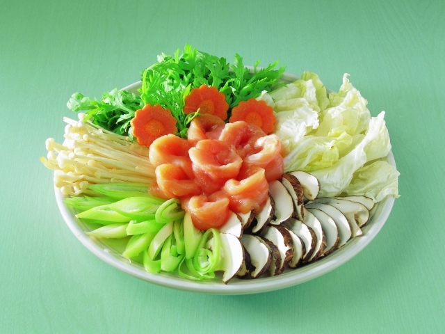 Тарелка с овощами и красной рыбой на зеленом фоне