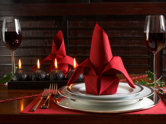 Красная салфетка на тарелке на столе с бокалами вина и свечами