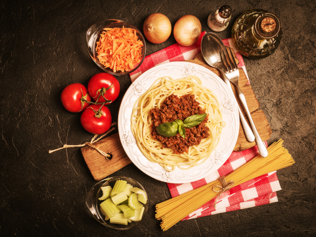 Спагетти с фаршем на столе с овощами